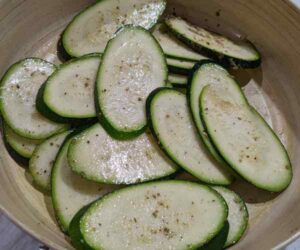 Zucchini slices in a bowl with seasoning