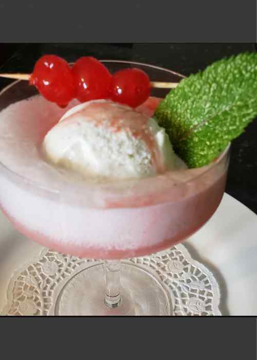 Fizzy Pink Drink in Cocktail Glass with Ice Cream , Cherries and Mint