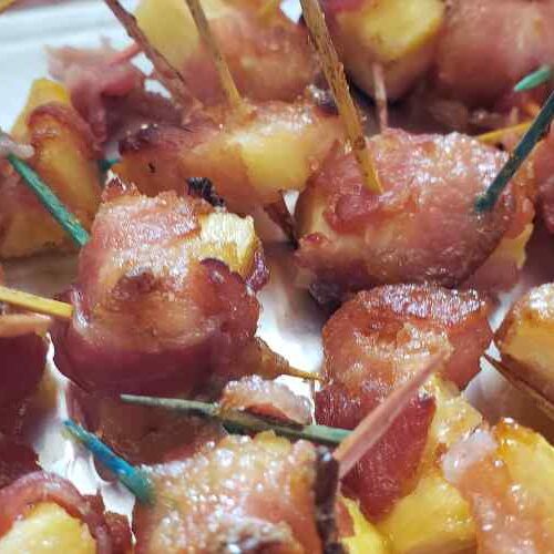 Chunks of pineapple wrapped in crispy bacon secured with toothpicks