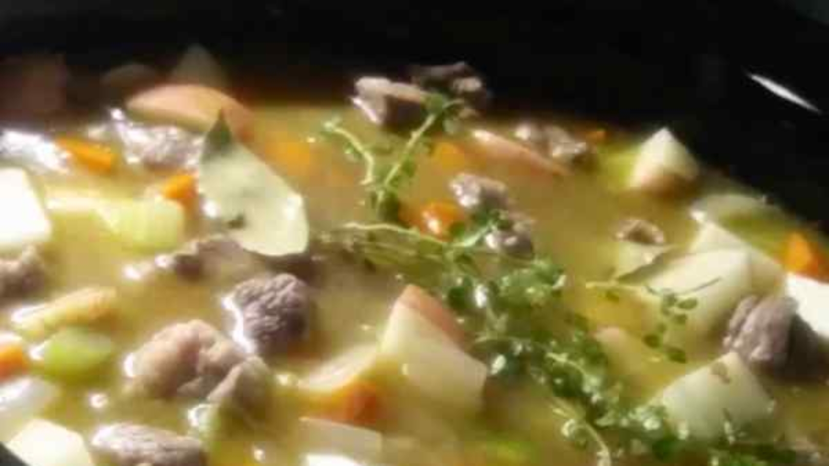 beef stew with vegetables potatoes and herbs sitting in a crock pot