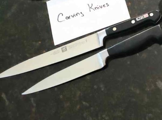 two carving knives sitting on a black granite counter top