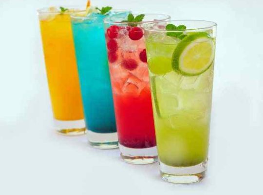 Colorful drinks in tall glasses with fruit