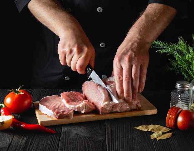 Chef cutting pork chops from loin